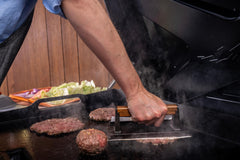 Traeger detail of cast iron burger press demonstrating weight for better sear