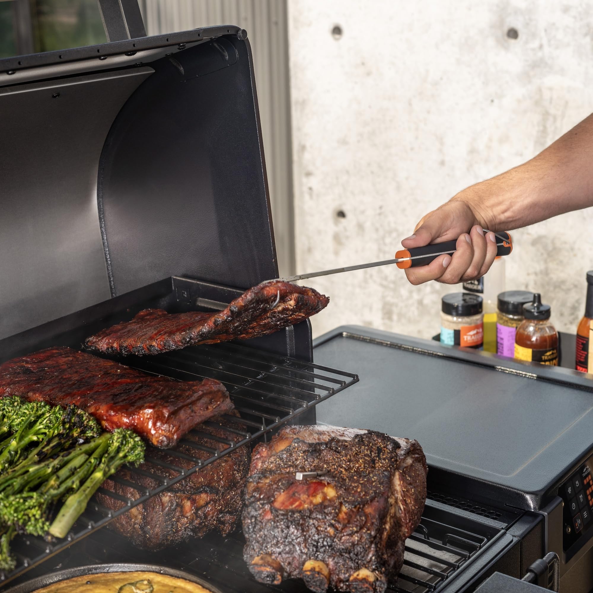 Traeger pig tail lifting ribs on grill demonstrating easier large-meat handling