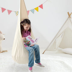 TRAVELBAIC child using cream pod swing reading, promoting calm focused play
