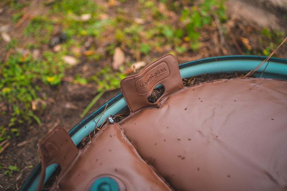 Vego garden next to garden hose for scale showing 16-gallon capacity benefit