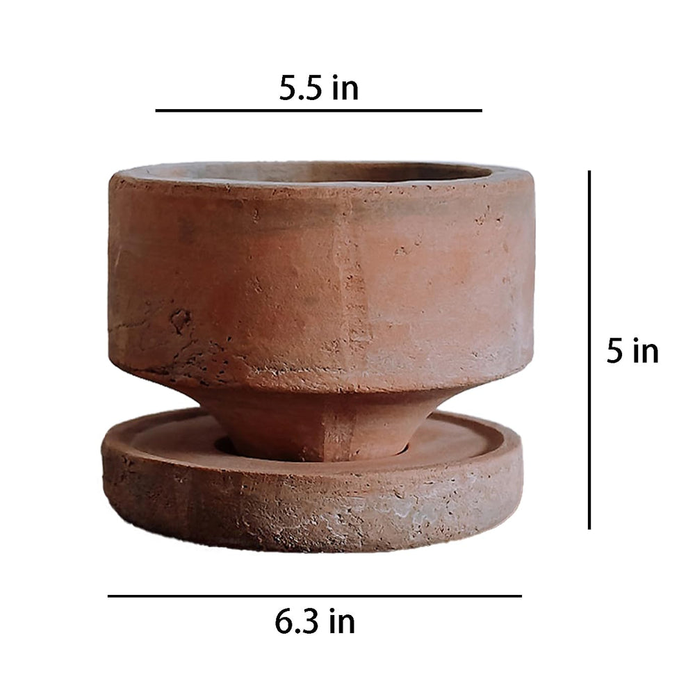 Wavy Studio terracotta pot with matching saucer holding a small herb plant, protecting surfaces