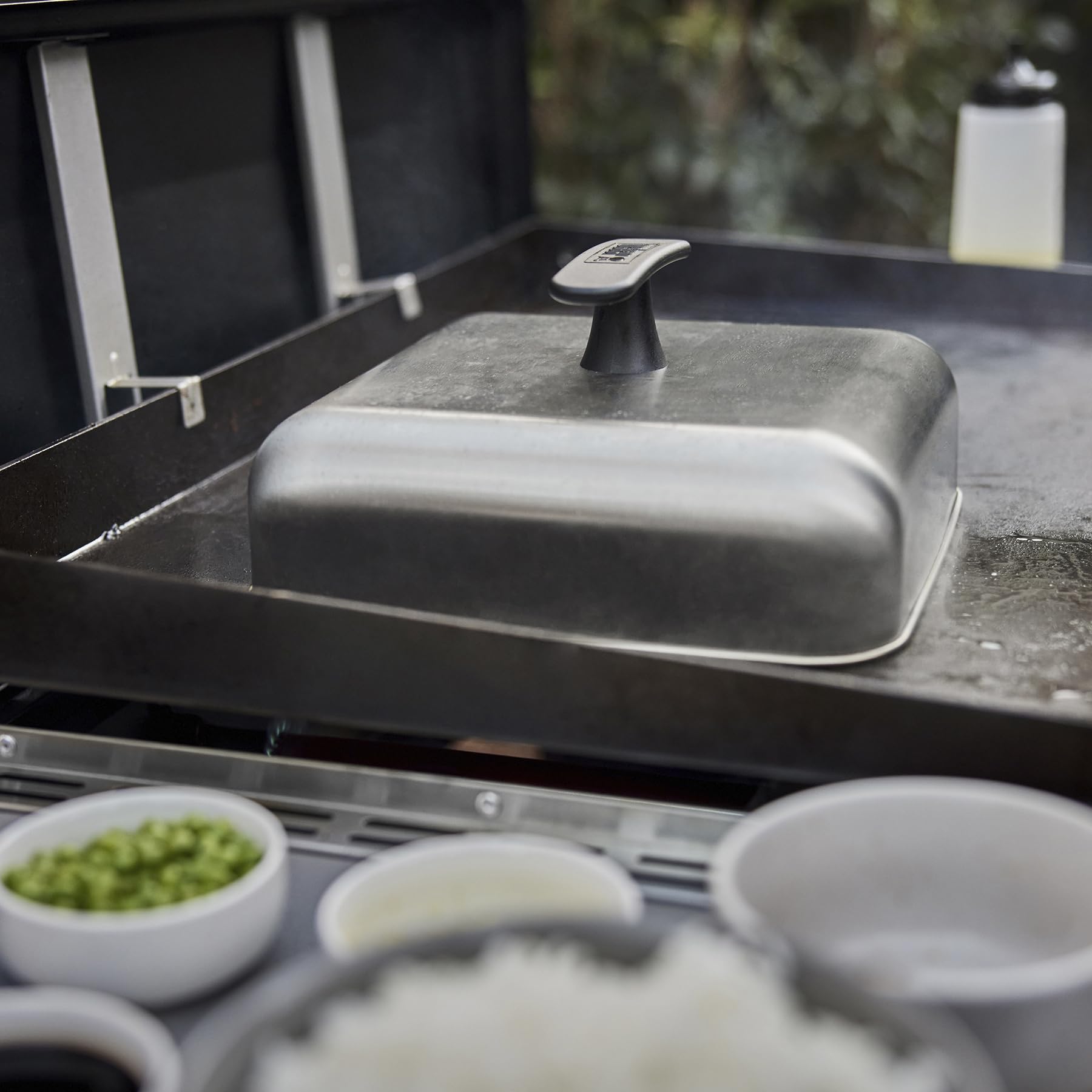 Weber dome in use melting cheese on burgers to create even, gooey topping