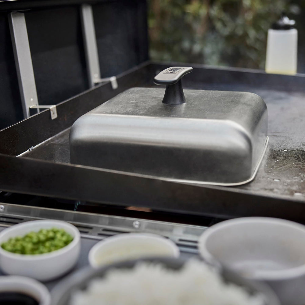 Weber dome in use melting cheese on burgers to create even, gooey topping