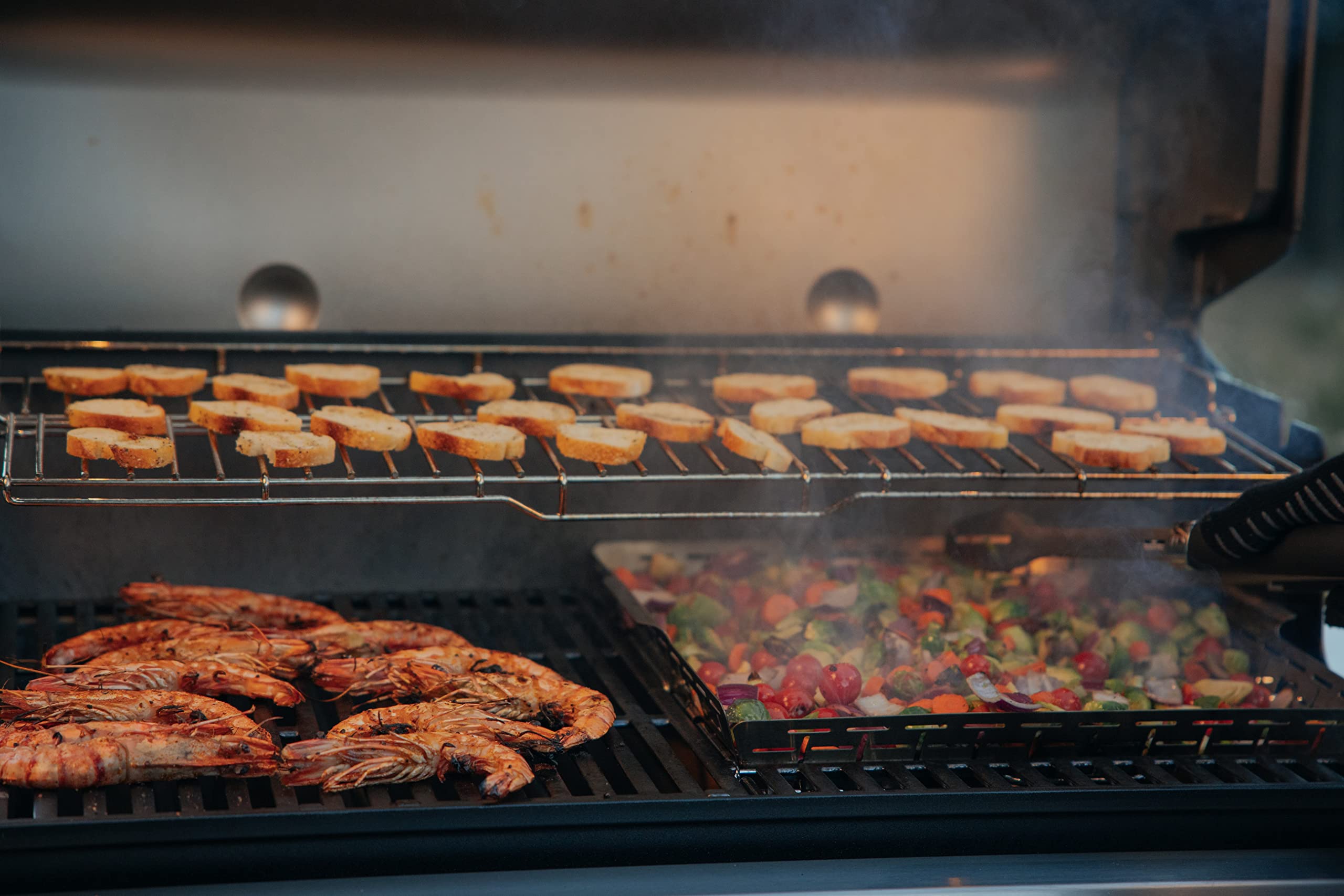 Frame stored beneath a right-side grate to show compact storage and easy swapability in the grill