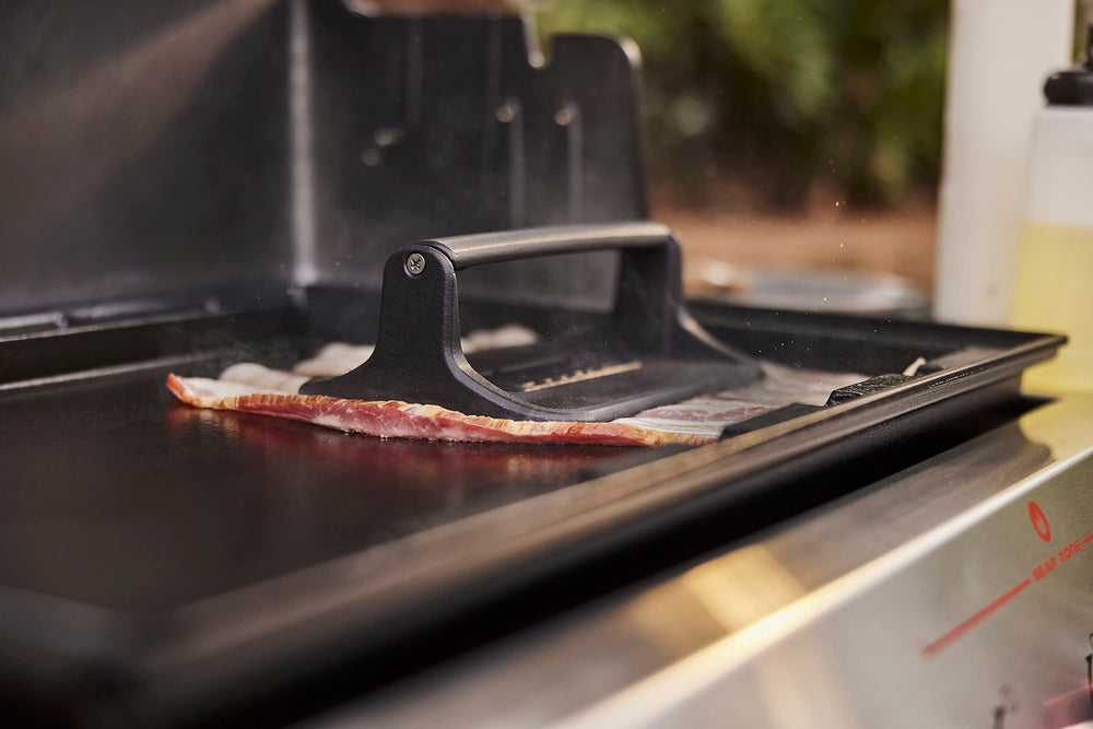 Weber press in use flattening bacon for even crisping and faster cook times