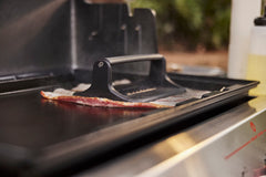 Weber press in use flattening bacon for even crisping and faster cook times