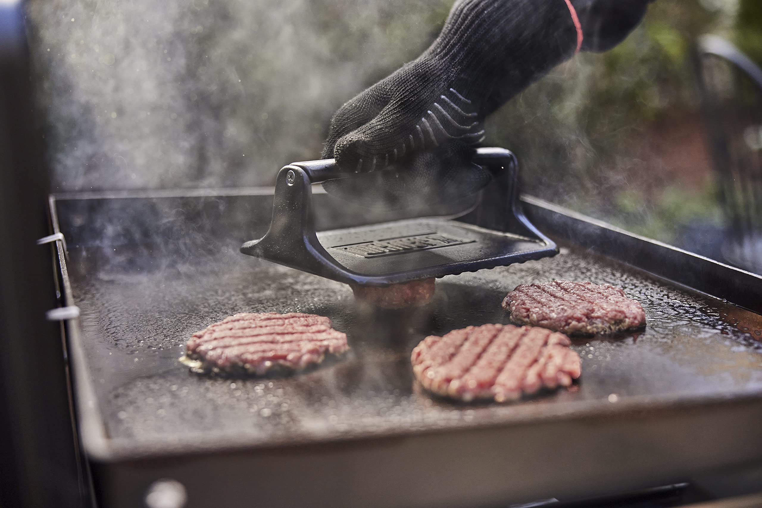 Weber press beside a burger to show scale and coverage for consistent smash burgers