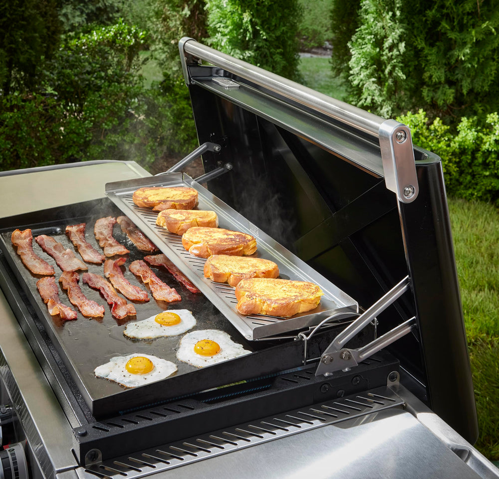 Weber warming rack beside a hand for scale showing roomy surface and practicality