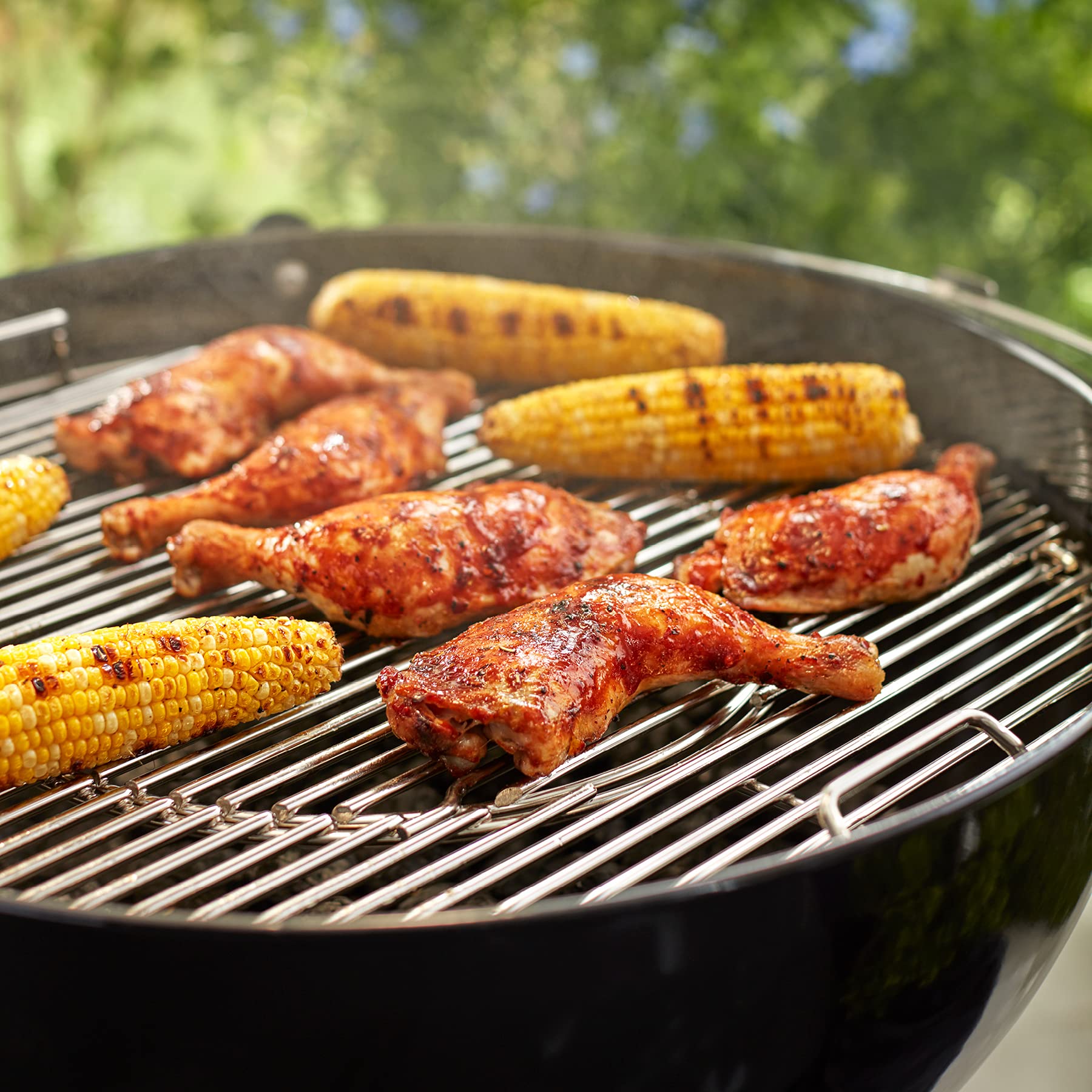 Weber grill in backyard with hinged grate for uninterrupted outdoor cooking